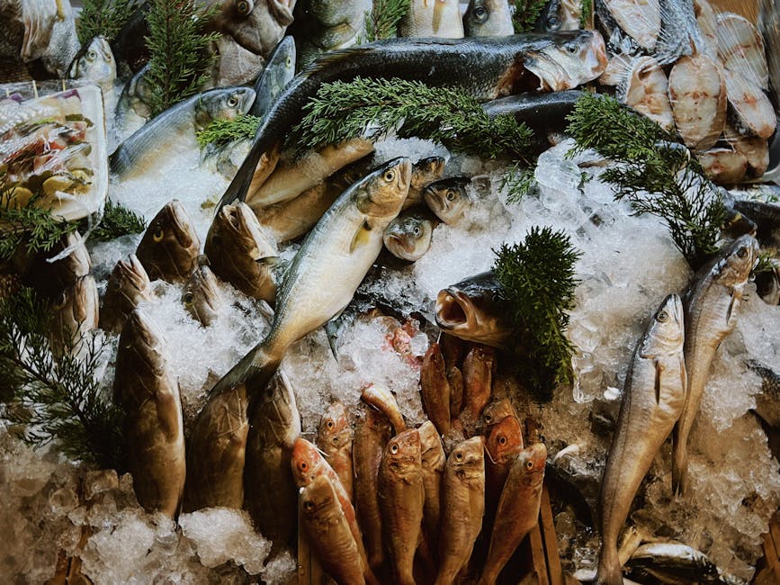 A vibrant array of fresh fish on ice, accented with green herbs, highlighting seafood variety.