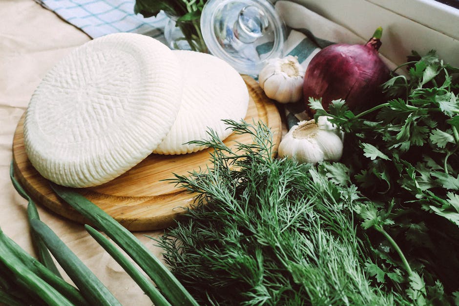 A wooden board with fresh cheese surrounded by herbs and vegetables, ideal for healthy eating.